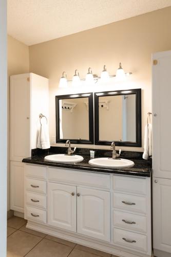 a bathroom with two sinks and two mirrors at Kihei Akahi A104 in Wailea