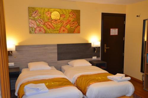 three beds in a hotel room with a painting on the wall at Beausite in Lausanne