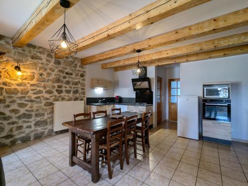 une grande cuisine avec une table et des chaises en bois dans l'établissement Gîte de charme en campagne, 5-8 pers., cheminée, nature, proche Pilat, activités à proximité - FR-1-582-269, à Saint-Romain-Lachalm