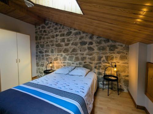 a bedroom with a bed and a stone wall at Gîte de charme en campagne, 5-8 pers., cheminée, nature, proche Pilat, activités à proximité - FR-1-582-269 in Saint-Romain-Lachalm