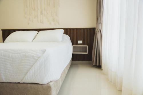 a bedroom with a bed with white sheets and curtains at Casa Serena in Ibagué