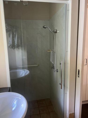 a shower with a glass door next to a sink at Kalua Motel in Bundaberg