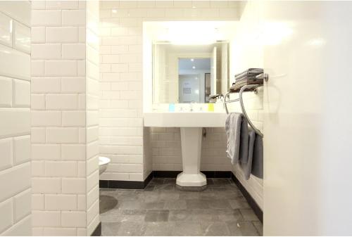 La salle de bains blanche est pourvue d'un lavabo et d'un miroir. dans l'établissement Baeten's bed and breakfast, à Gand