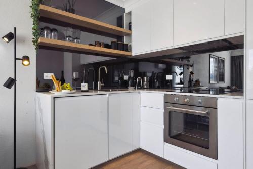 a kitchen with white cabinets and an oven at Horizons 410 in Jindabyne