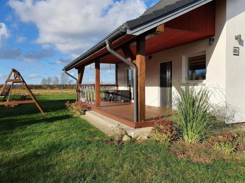a house with a deck and a swing at House near S owi ski Park and Sandy Beach in Smołdzino