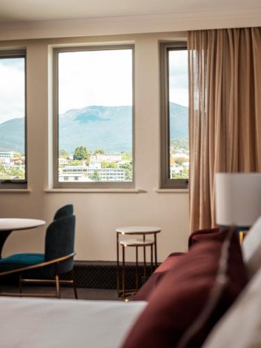 a hotel room with windows and a table and chairs at Lenna Of Hobart in Hobart