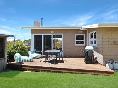 a wooden deck with a table and chairs on a house at Cutback Cottage in Scamander