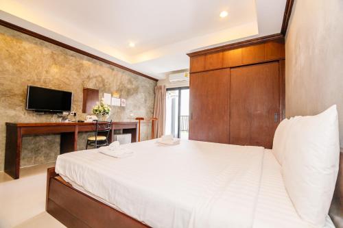 a bedroom with a large white bed and a desk at The Glasshouse place in Trang