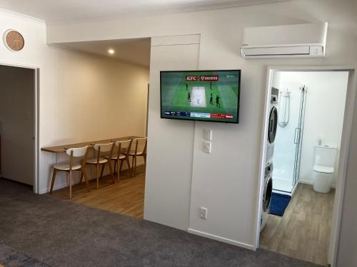 a room with a tv on a wall with a dining room at Close, Convenient & Comfortable in Cambridge