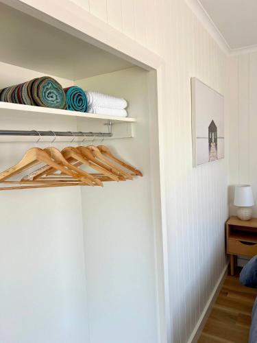 a room with a closet with wooden shelves and towels at Magpie Sands - Ocean Views & Seaside Luxury - Steps to beach in Aldinga Beach