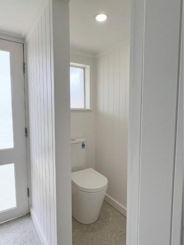a bathroom with a toilet and a window at Magpie Sands - Ocean Views & Seaside Luxury - Steps to beach in Aldinga Beach