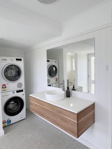 a bathroom with a sink and a washer and dryer at Magpie Sands - Ocean Views & Seaside Luxury - Steps to beach in Aldinga Beach