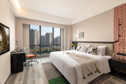 a bedroom with a large bed and a desk and window at Somerset Chayuan Chongqing in Chongqing