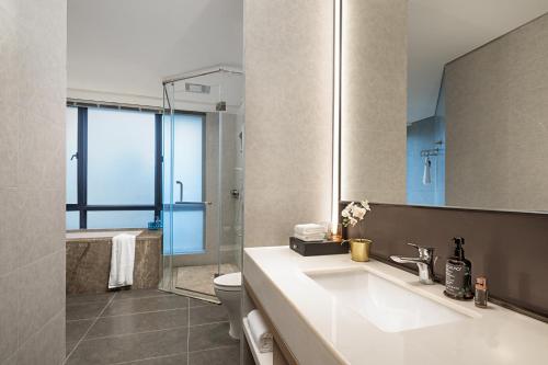 a bathroom with a sink and a toilet and a mirror at Somerset Chayuan Chongqing in Chongqing