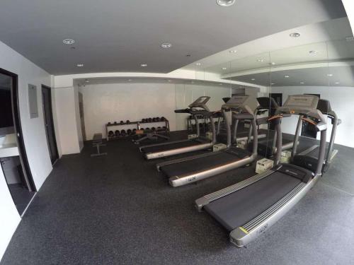 a gym with a row of treadmills and mirrors at Portovita Towers in Manila