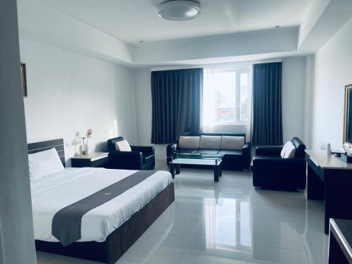 a hotel room with a bed and a couch and chairs at Vera Hotel in Angeles
