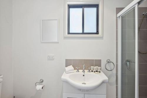 Un baño blanco con lavabo y ducha. en Apres 9, en Jindabyne