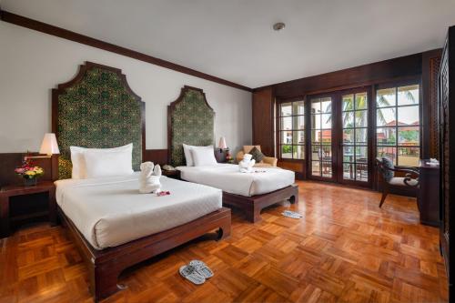 two beds in a room with wooden floors and windows at Ayodya Resort Bali in Nusa Dua