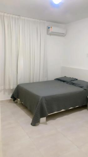 a bedroom with a bed and a window with white curtains at Casa pra temporada 3 quartos 10 km de Cabo frio in São Pedro da Aldeia