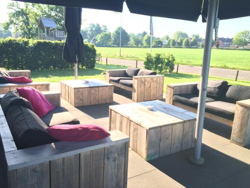 a patio with couches and tables and an umbrella at De Slaapfabriek vakantiehuis en trainingslocatie in Teuge