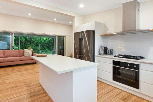 a kitchen with white countertops and a living room at Reflections Evans Head - Holiday Park in Evans Head