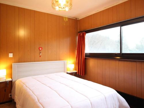 une chambre avec un grand lit blanc et une fenêtre dans l'établissement Bel F2 avec balcon, parking privé et ascenseur - Mont-Dore - FR-1-415-39, à Le Mont-Dore
