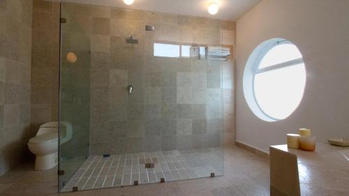 a bathroom with a shower with a toilet and a window at Casita Perla Sustainable Villa with Mountain View, Long Pool, King, Grill in Texcalpan
