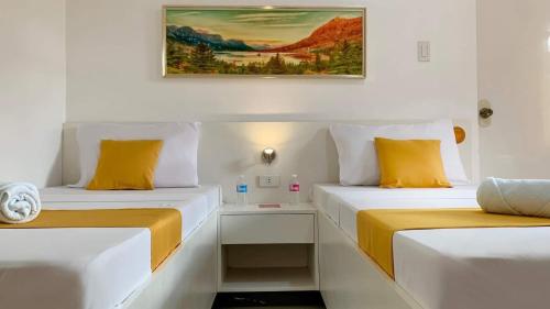two beds sitting next to each other in a room at Bohol Emerelle's Tourist Inn in Dauis