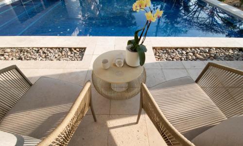 a table with chairs and a vase with flowers on it at Casita Perla Sustainable Villa with Mountain View, Long Pool, King, Grill in Texcalpan