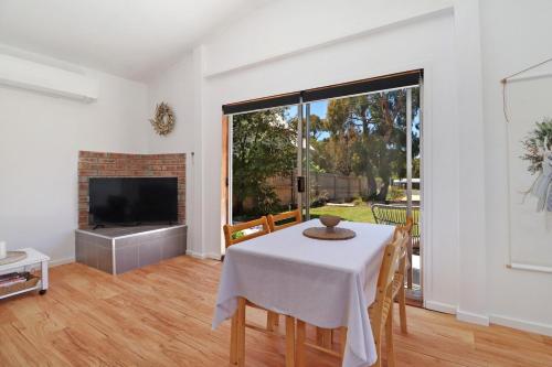 a dining room with a table and a television at Two Gums Cottage in St Helens
