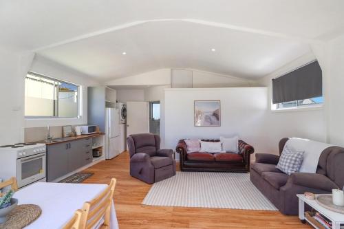 a living room with two couches and a kitchen at Two Gums Cottage in St Helens