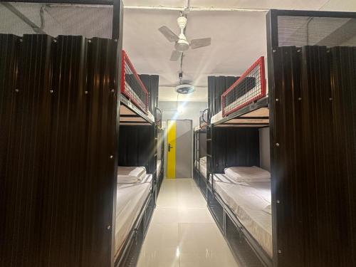 a hallway with three bunk beds in a room at Travotale Hostel and CoWork Koregaonpark Pune in Pune
