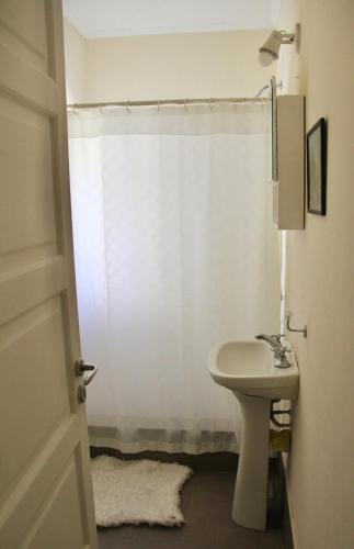 a bathroom with a sink and a white shower curtain at La Elegida in San Antonio de Areco