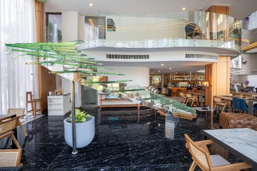 a glass staircase in a restaurant with tables and chairs at The Blue Mavi Hotel in Chalong 