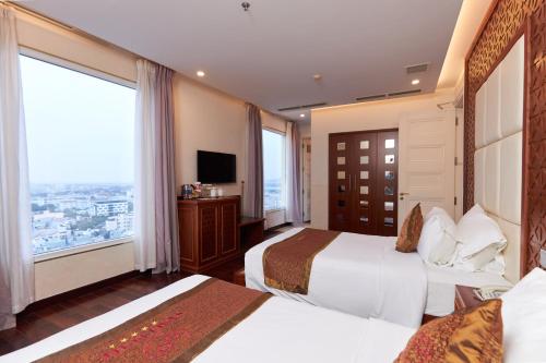 a hotel room with two beds and a large window at Samdi Grand Danang in Da Nang