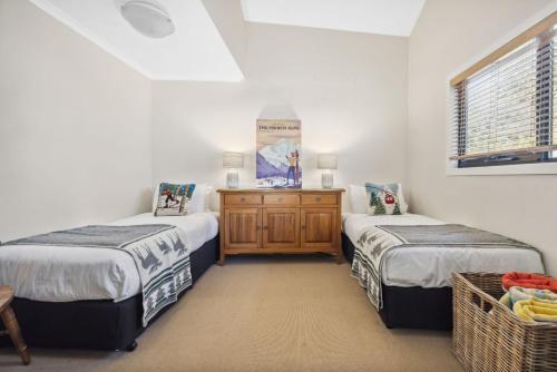 1 dormitorio con 2 camas y tocador de madera en Albina, en Thredbo