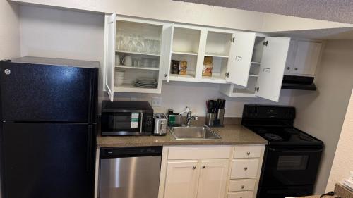 a kitchen with white cabinets and a black refrigerator at A luxury studio apartment, in Salt Lake City
