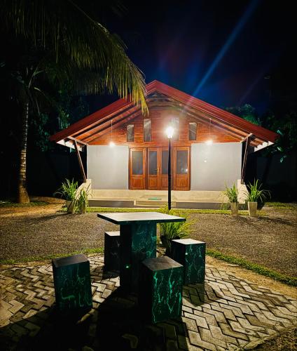 a table and stools in front of a house at night at Induwara Arana in Kurunegala