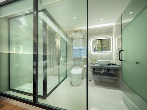 a bathroom with a glass shower and a sink at FenghuangQixin Guesthouse in Fenghuang