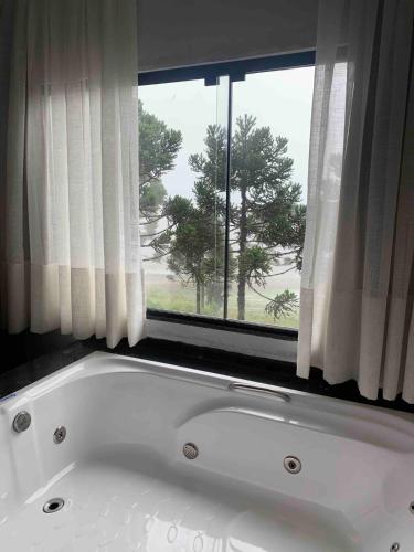 a white bath tub in front of a window at Casa de Campo Completa Cabanas Monte Sierra in Urupema