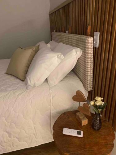 a bed with white pillows and a remote control on a table at Casa de Campo Completa Cabanas Monte Sierra in Urupema