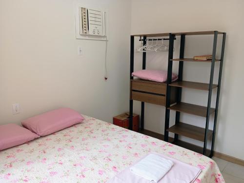 una camera con letto con lenzuola rosa e mensola di Amplo apartamento para aluguel diário numa das melhores praias de SC. a Meia Praia