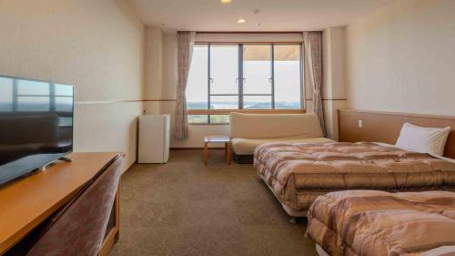 a hotel room with two beds and a flat screen tv at Hotel Cocoland in Ube