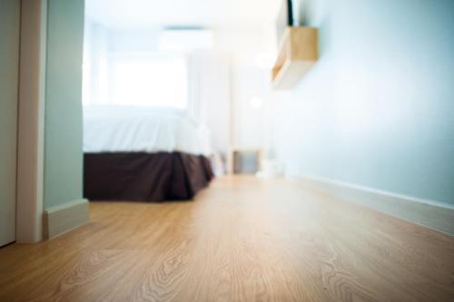 an empty room with a bed and a wooden floor at KENCOZY accommodation in Bangkok