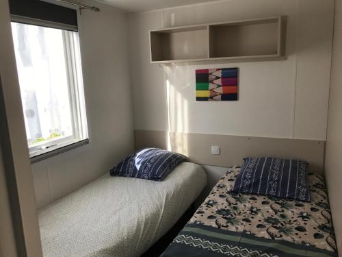 une petite chambre avec un lit et une fenêtre dans l'établissement MOBIL HOME 2 CHAMBRES 1 SDB - DOMAINE DE KERLANN, à Pont-Aven