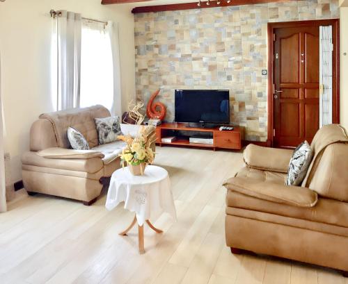 Una sala de estar con dos sofás y un televisor. en Spacious House in Flic en Flac with Shared Pool, en Flic en Flac
