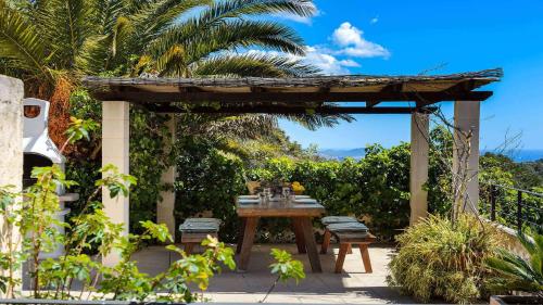 eine Terrasse mit Tisch und Stühlen unter einer Pergola in der Unterkunft Villa Cana Romero II Sea Views in Sant Josep