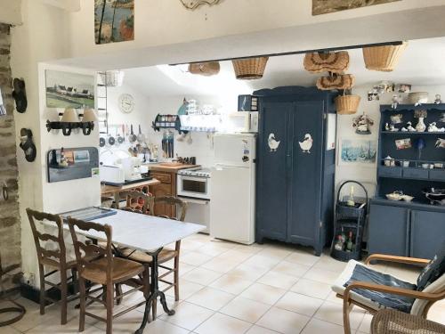 une cuisine avec une table et un réfrigérateur blanc dans l'établissement Maison paisible à Moëlan-sur-Mer avec jardin et barbecue, à Moëlan-sur-Mer