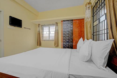 a bedroom with a large bed with white pillows at Super Hotel O Vsv Guest House in Chennai