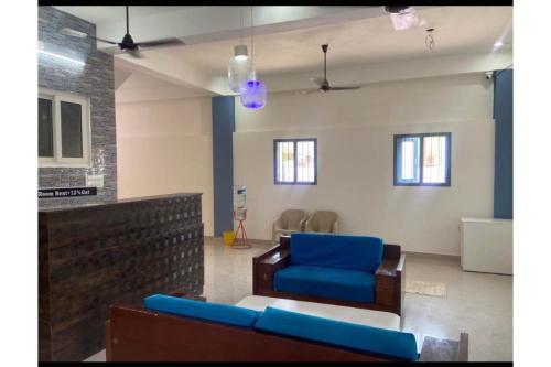 a living room with a blue chair and a couch at Super Hotel O Vsv Guest House in Chennai